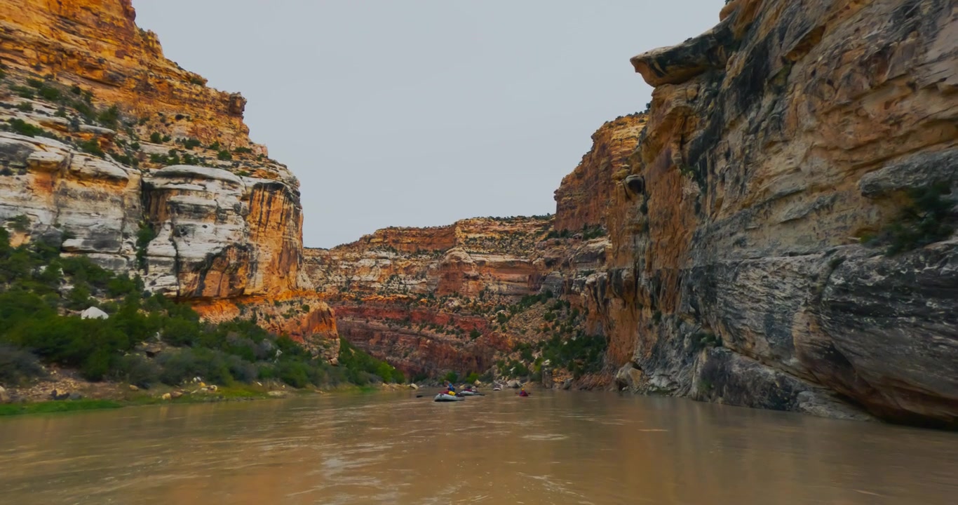 Spostandosi tra uno stretto passaggio di canyon con scogliere a strati sopra il fiume, esperienza di pack rafting nel backcountry