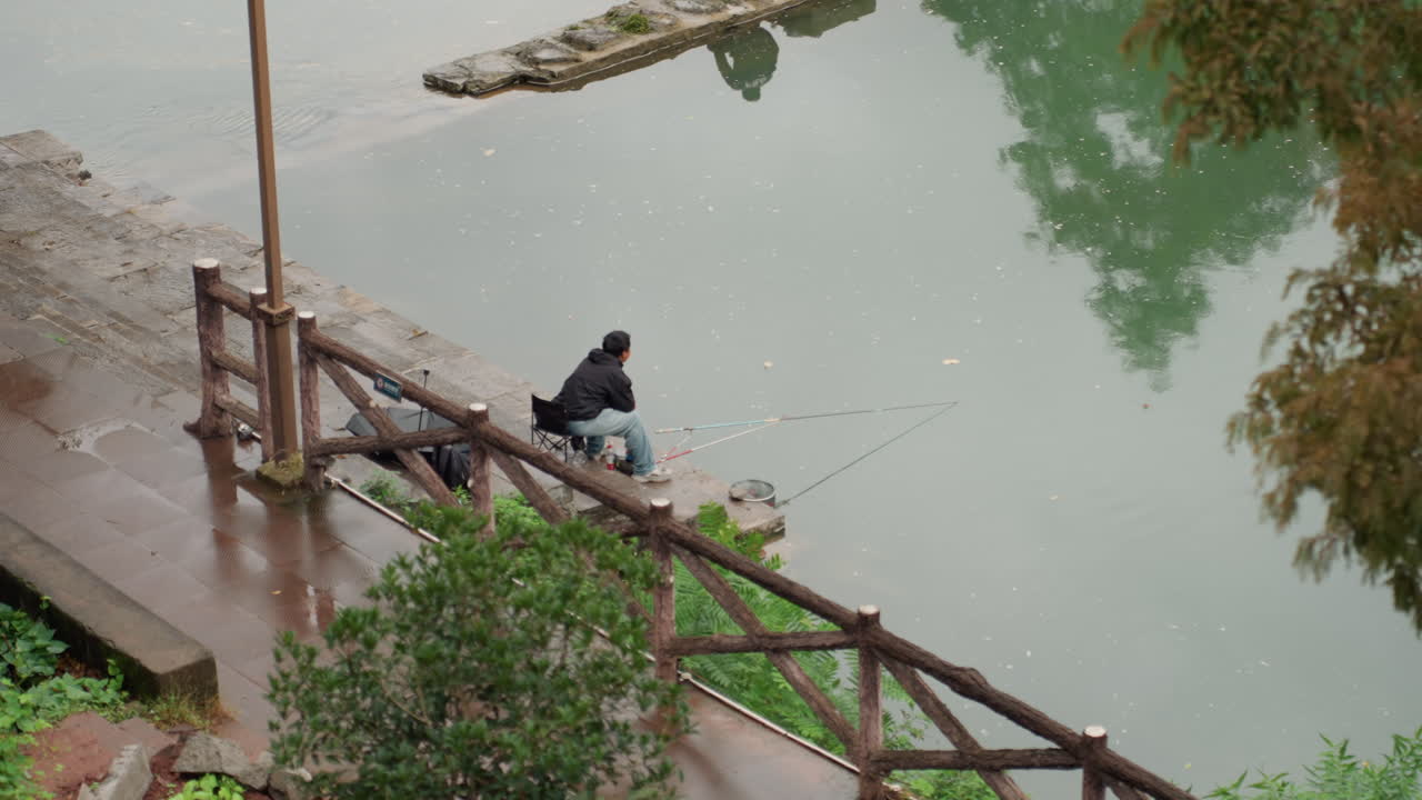 Pemandangan menenangkan di tepi perairan yang tenang dengan peralatan memancing. Memancing di pagi hari yang damai di samping air yang tenang dan tentram. Pagi yang hening dan sejuk dihabiskan memancing di tepi kolam yang tenang dengan perlengkapan.