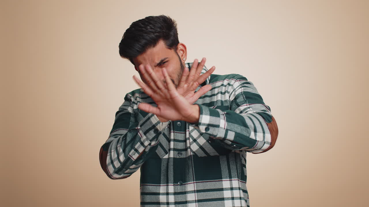 Afraid indian man closing eyes with hand showing stop gesture confused shy scared to watch awful