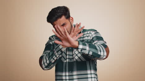 afraid indian man closing eyes with hand showing stop gesture confused shy scared to watch awful