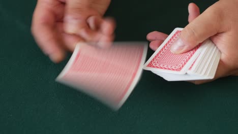 close-up of a casino dealer's hands as he deals playing cards and then fans out the cards on the table