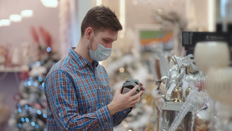 A-man-in-a-protective-mask-in-a-jewelry-store-and-garlands-with-toys-for-Christmas-trees-and-at-home.-Christmas-garlands-and-decor