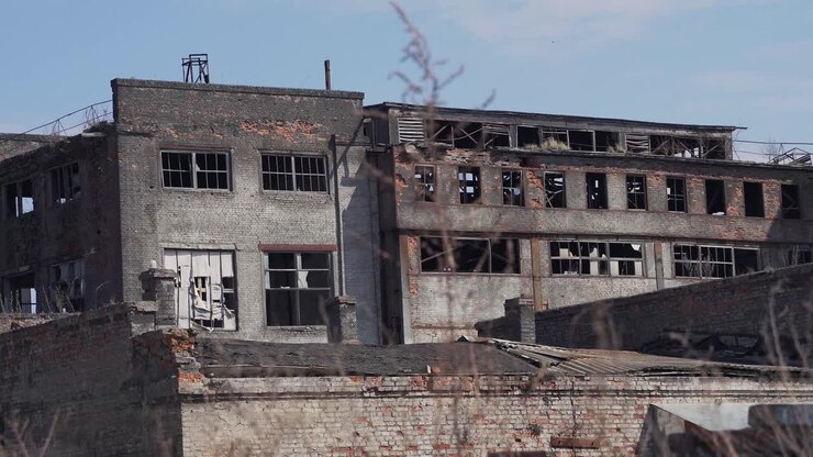 Edifici in cemento e mattoni rotti e distrutti di una vecchia fabbrica abbandonata con finestre rotte. Edifici industriali in Ucraina.