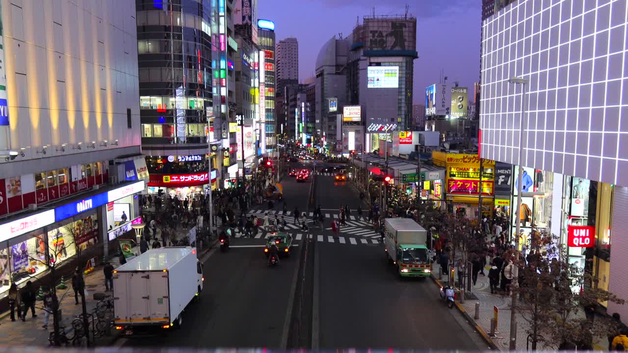 Busy street in Shinjuku Tokyo city, road center with people walking and crossing, 4K tilting up