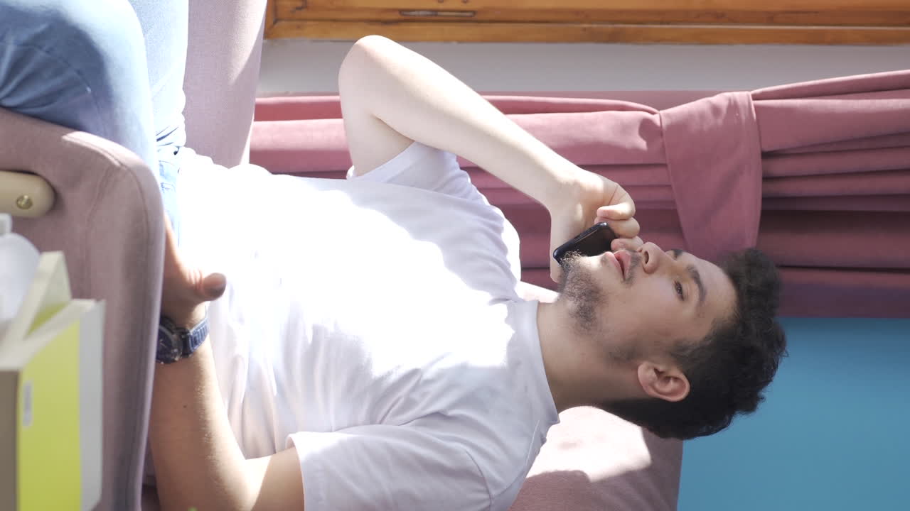 그 남자가 전화로 얘기하고, 논쟁하는 수직 비디오입니다.