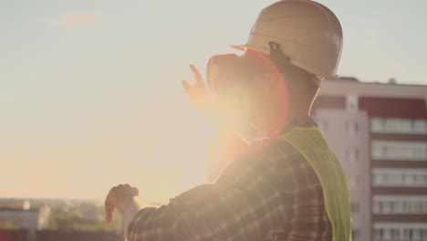 engineer the builder on the roof of the building stands in vr glasses and moves his hands using the interface of the future. futuristic engineer of the future.