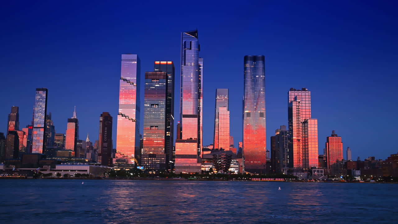 New York, USA, 8 July 2025: Setting sun colors the facades of the stunning modern high-rises. New York skyline from the riverscape at sunset