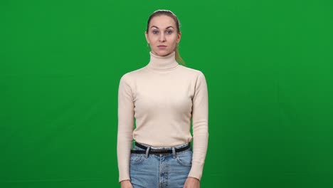 mujer estricta señalando a la cámara de pie en la pantalla verde. retrato de la exigente dama caucásica posando en el fondo chromakey mirando la cámara