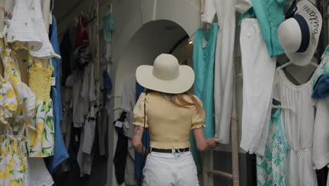 viajero caucásico mirando ropa de mujer hermosa y accesorios colgando a lo largo de un callejón estrecho en italia