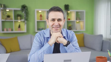 Man-working-online-from-his-home-looking-at-camera-and-laughing.