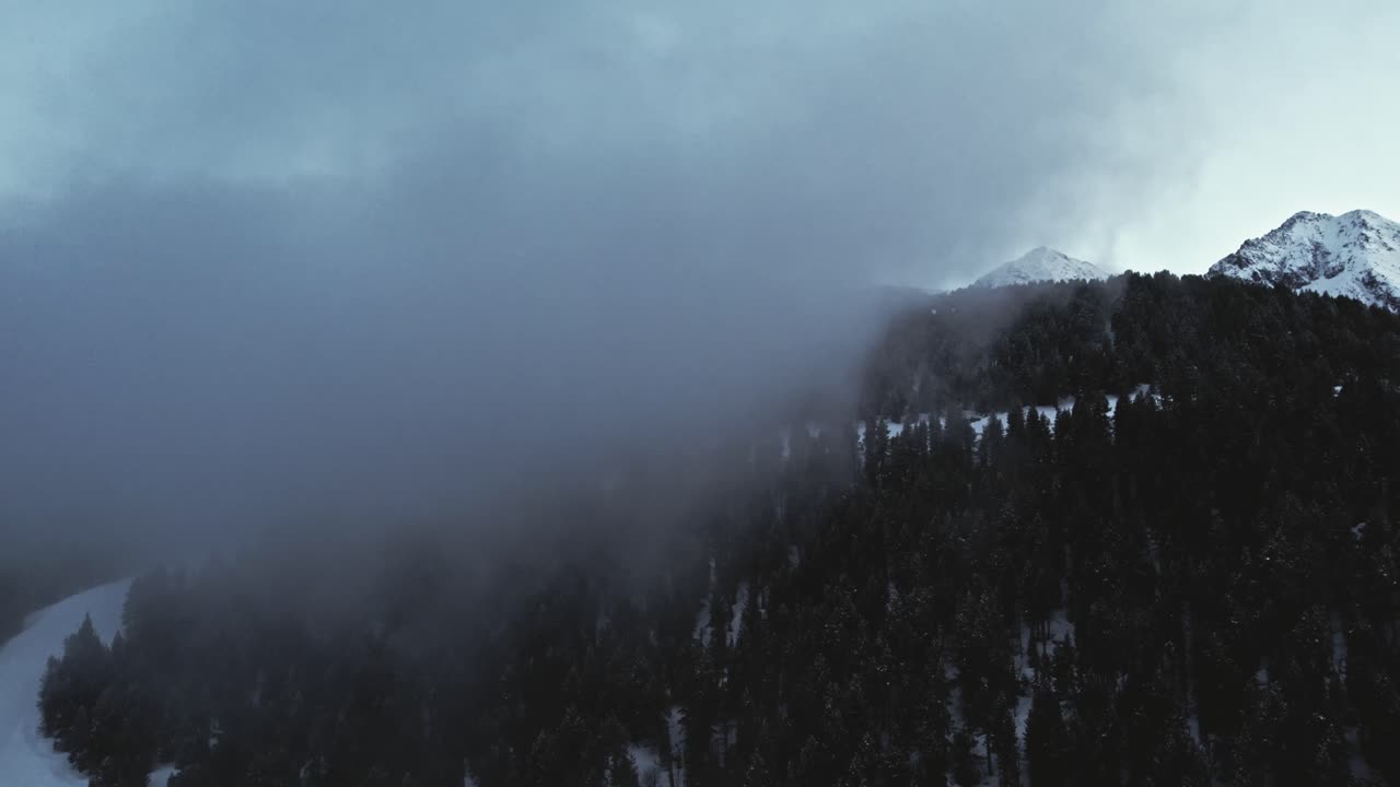 눈 덮인 고산 산의 스키 슬로프에서 구름 속으로 날아가는 드론