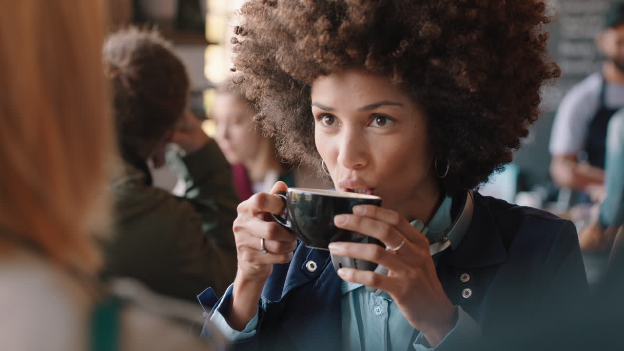 hermosa mujer de raza mixta con peinado afro charlando con un amigo en un café bebiendo café socializando disfrutando de la conversación pasando el rato en un restaurante ocupado