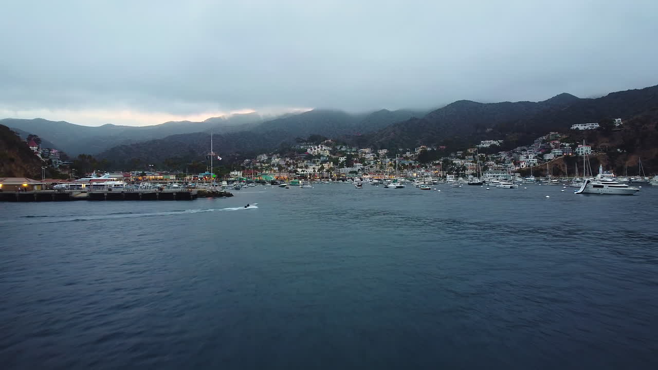 disparo de drones hacia adelante cuando la lancha rápida entra en el puerto deportivo de avalon bay en una tranquila mañana nublada, santa catalina, california