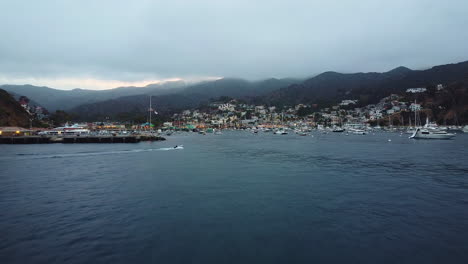 Drone-Forward-Shot-as-Speedboat-Enters-Avalon-Bay-Marina-on-Quiet-Cloudy-Morning,-Santa-Catalina,-California