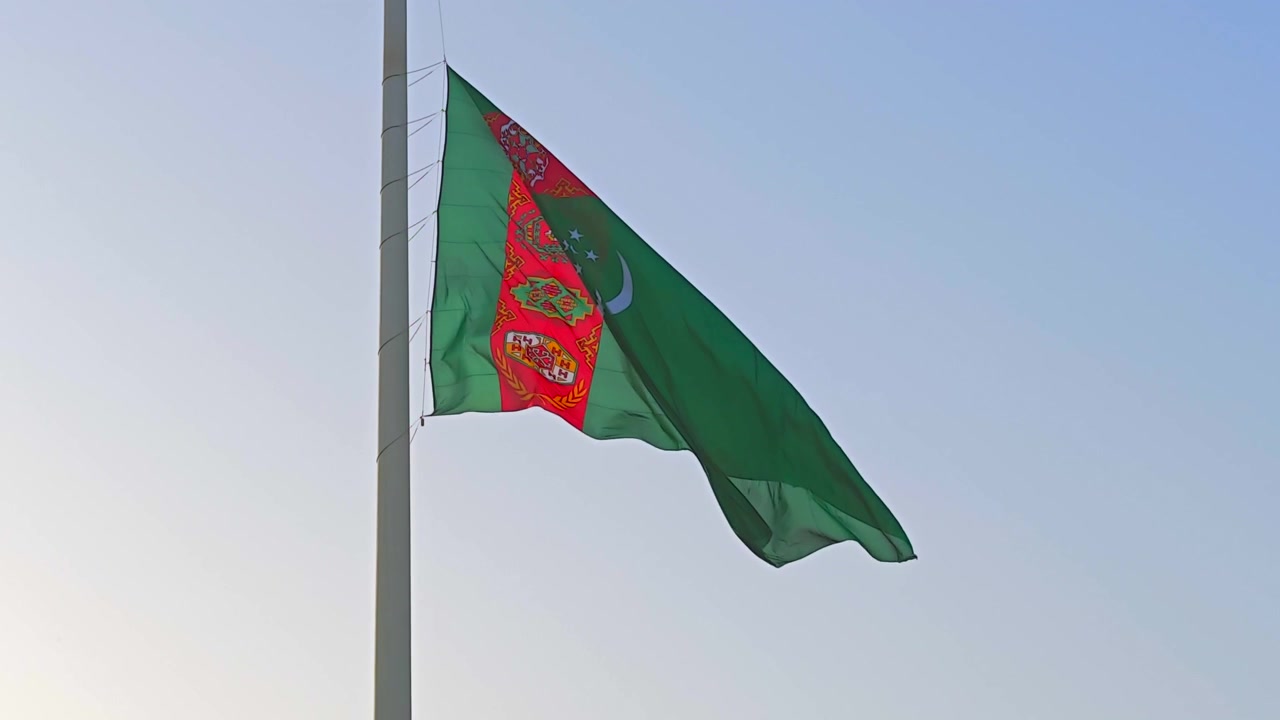 Bandera de Turkmenistán ondeando contra un cielo azul claro