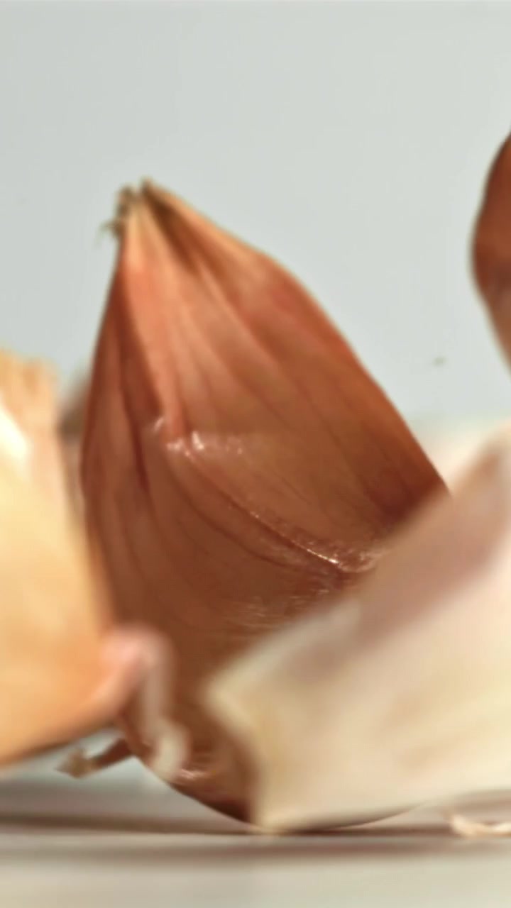 Spicchi d'aglio che cadono su sfondo bianco al rallentatore