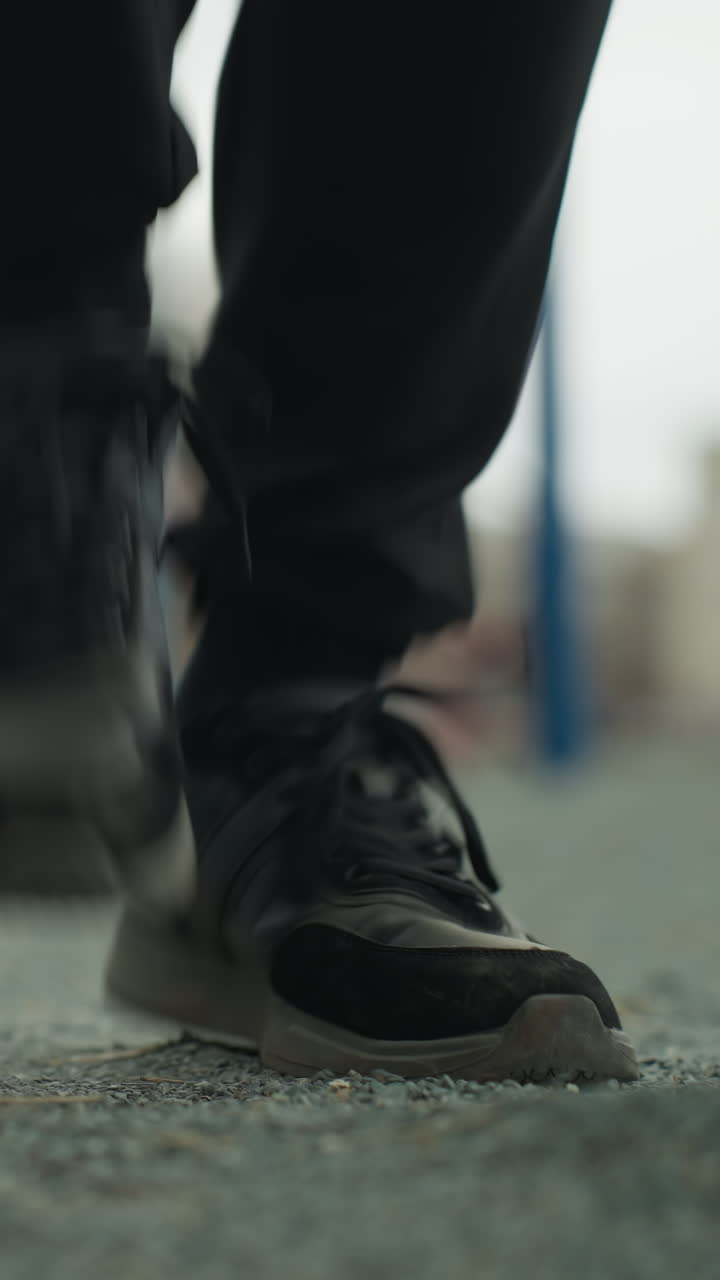 primer plano de las piernas de una persona corriendo cerca de una barra de hierro azul y hierba verde, un banco es visible detrás, con una vista borrosa de una casa amarilla pintada en la distancia