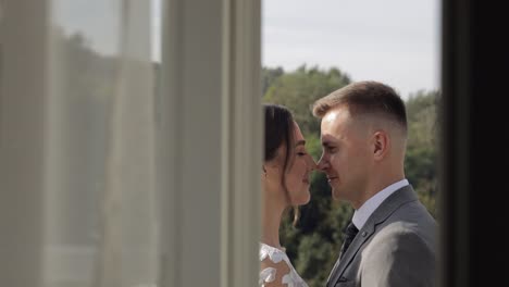 caucasian newlyweds bride embracing groom on balcony in hotel room, slow motion