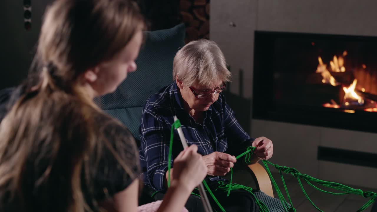 할머니와 손녀가 벽난로 에서 함께 뜨개질
