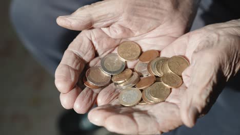 problem of high rate poverty among the people in retirement, senior man holding stack of coins in his wrinkled hands, old man calculating miserable pension income and needs financial social assistance