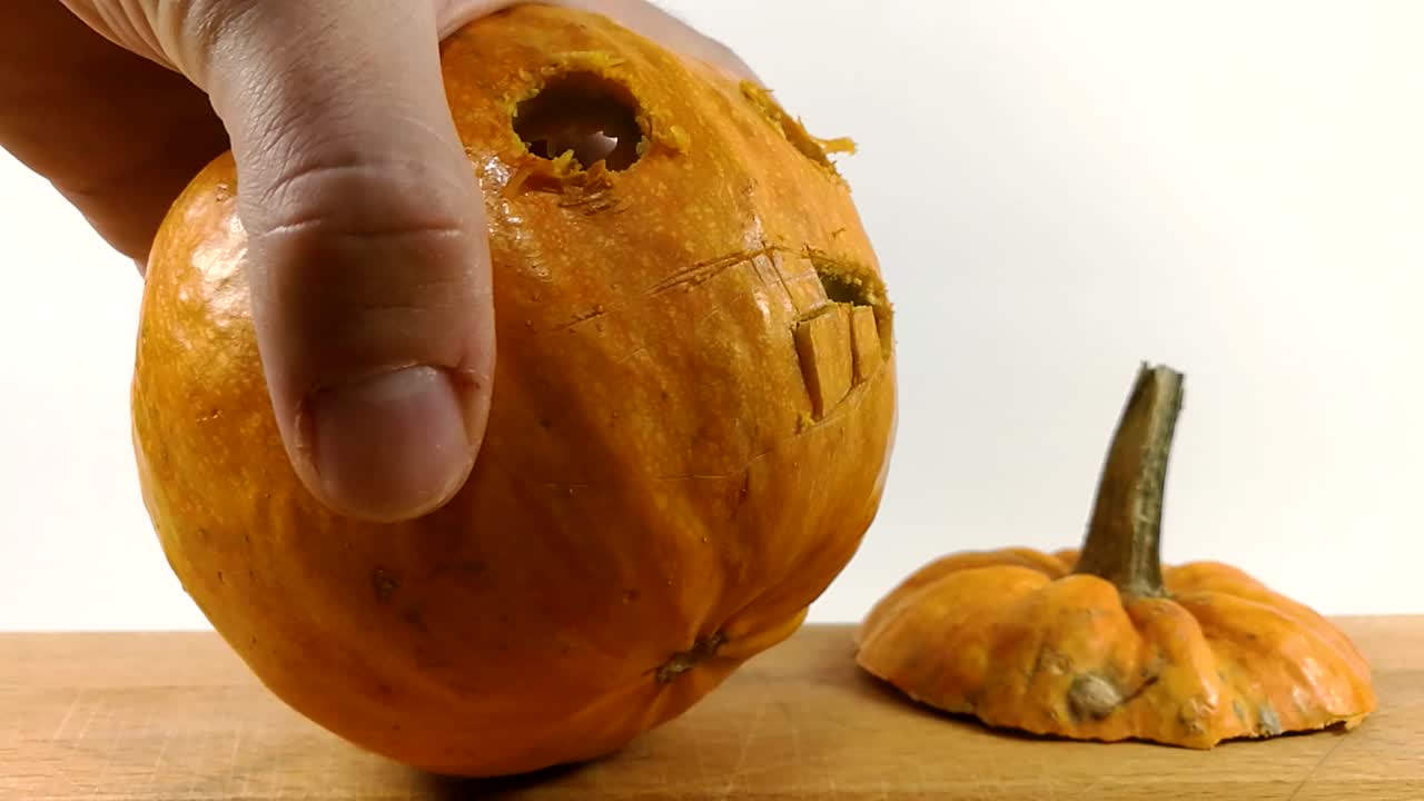 Carving pumpkin part 4, Person carving teeth into Halloween pumpkin with a small pointy serrated knife on wooden chopping board, STILL, ISOLATED