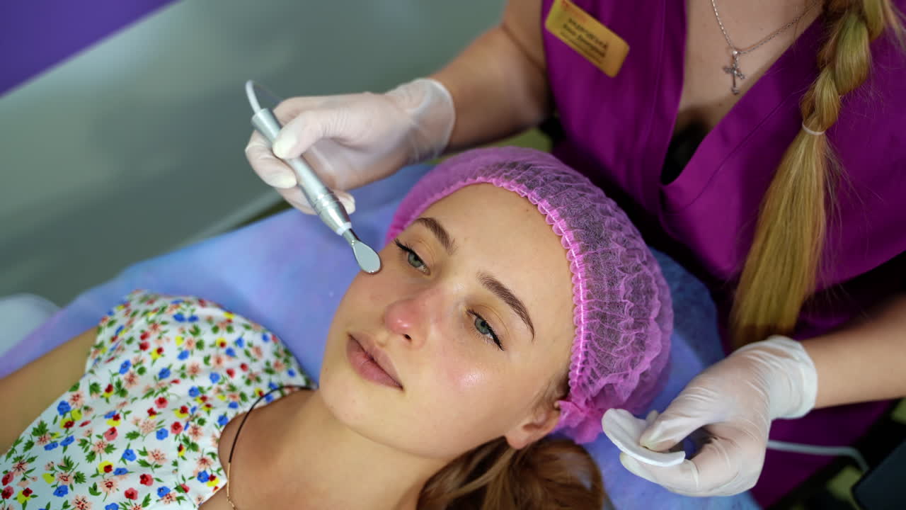 Cosmetology. Woman in clinic receiving stimulating electric facial treatment. Closeup of young female face during microcurrent therapy.