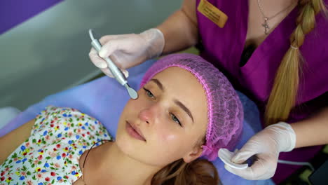 cosmetology. woman in clinic receiving stimulating electric facial treatment. closeup of young female face during microcurrent therapy.