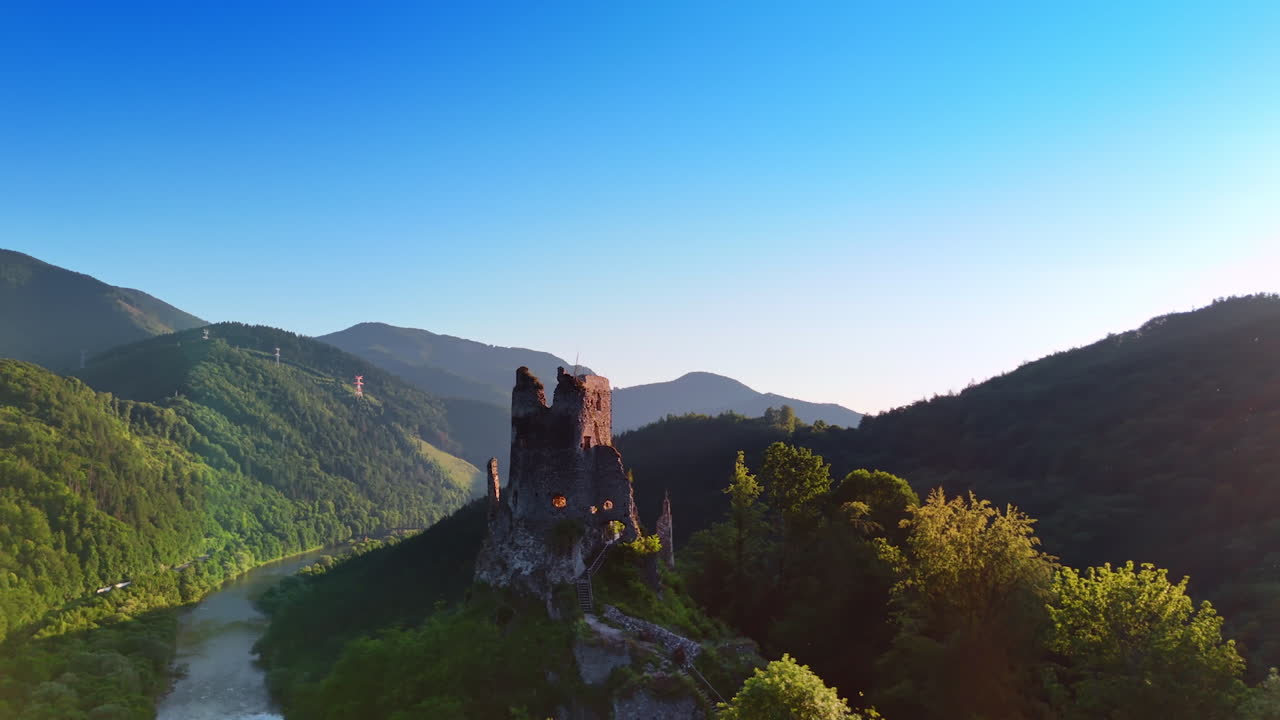 Ruins of the ancient castle or church located on the top of the hill. Spectacular mountains with river at foot at backdrop.