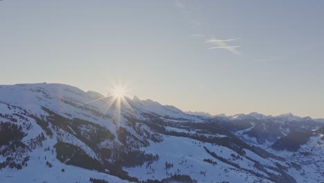 Toma-Aérea-Del-Amanecer-Que-Muestra-La-Silueta-De-Picos-Cubiertos-De-Nieve