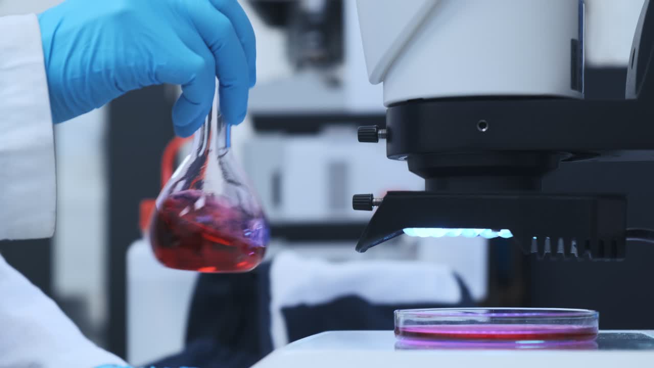 científico mezclando líquido rosado en los frascos de vidrio