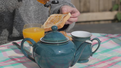 person pours honey on buttered toast at english breakfast, slow motion