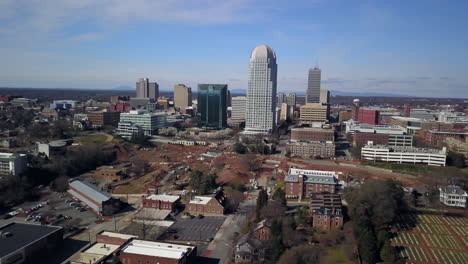 Aerial-flying-toward-Winston-Salem-North-Carolina-with-the-city-looming-in-the-distance