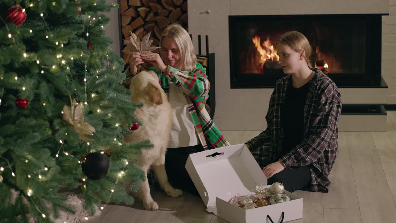 Family Decorating Christmas Tree with Dog by Fireplace