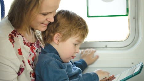 Un-Niño-Pequeño-Con-Una-Almohadilla-Sentado-En-El-Regazo-De-Su-Madre-En-El-Tren