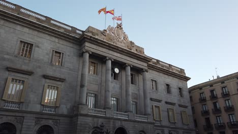 Fachada-De-Verano-Del-Edificio-Gubernamental-En-España,-Barcelona,-Palau-De-La-Generalitat-Con-Bandera-De-España-Ondeando-En-El-Cielo.