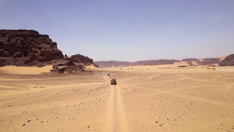 Off-Road-Vehicle-Driving-On-Sand-Dunes-Of-Desert-In-Djanet,-Algeria---aerial-drone-shot