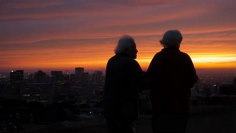 elderly couple watching sunset over city