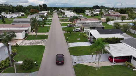 aerial tracking shot of black car in street in american neighborhood with palm trees. cape coral city, florida. wide shot.