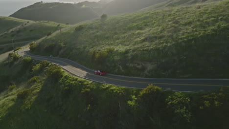 Wunderschöne-Drohnenaufnahme-Aus-Der-Luft-Zeigt-Einen-Roten-Porsche-1993-Carrera,-Der-Bei-Sonnenuntergang-Zur-Goldenen-Stunde-Durch-Die-Berge-Von-Malibu-Fährt