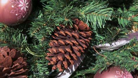 piñas secas de navidad y adornos de bolas rojas se ven colgando de un pino de navidad decorado