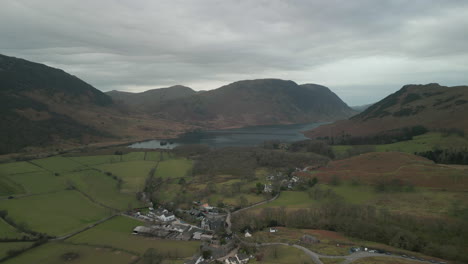 flying over quaint english village towards lake and mountains at buttermere english lake district uk