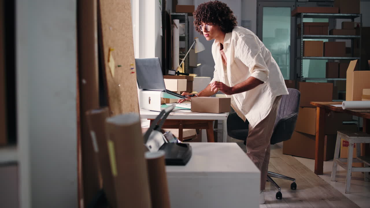 Young Man Preparing Package for Shipping in Small Business Office