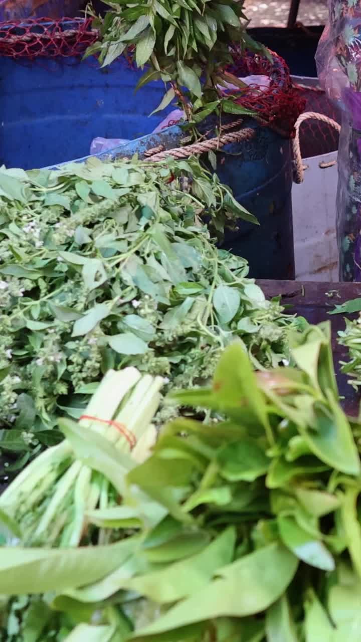 persona clasificando verduras de hojas en un puesto de mercado