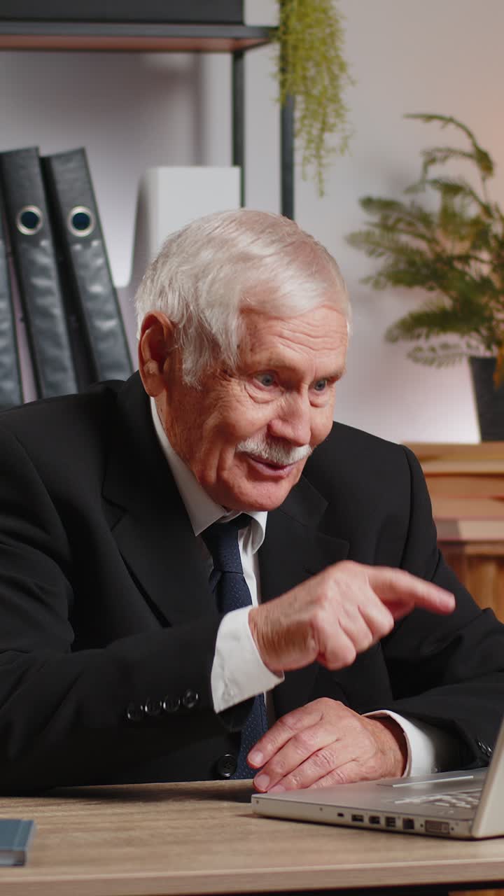 Senior businessman working on laptop at home office desk talk on online communication video call