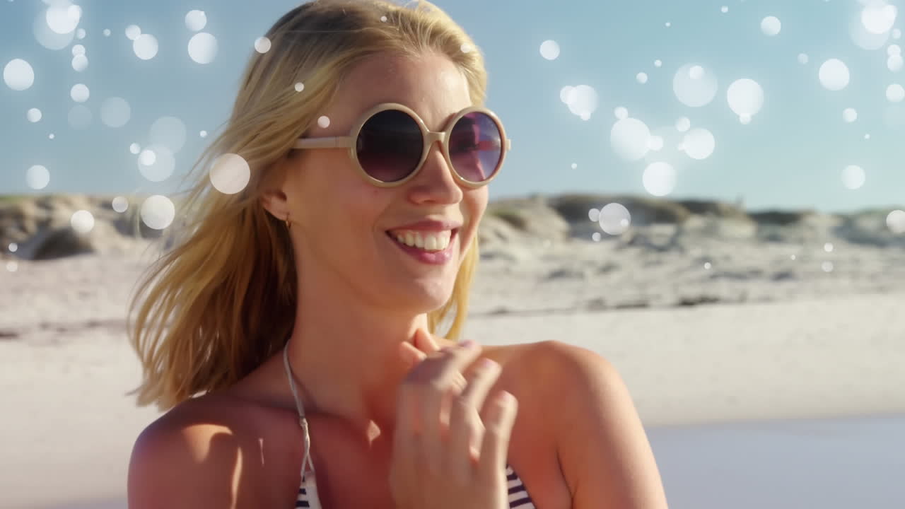 Bella donna caucasica in costume da bagno con occhiali da sole in spiaggia.