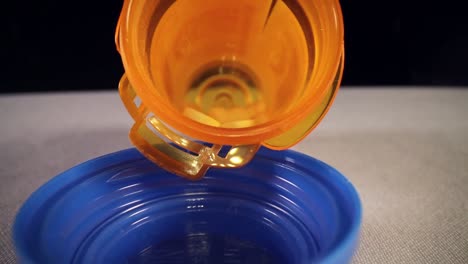 tirando rápidamente de toda la longitud de un frasco de píldoras recetadas de color naranja, revelando la tapa azul vacía del frasco