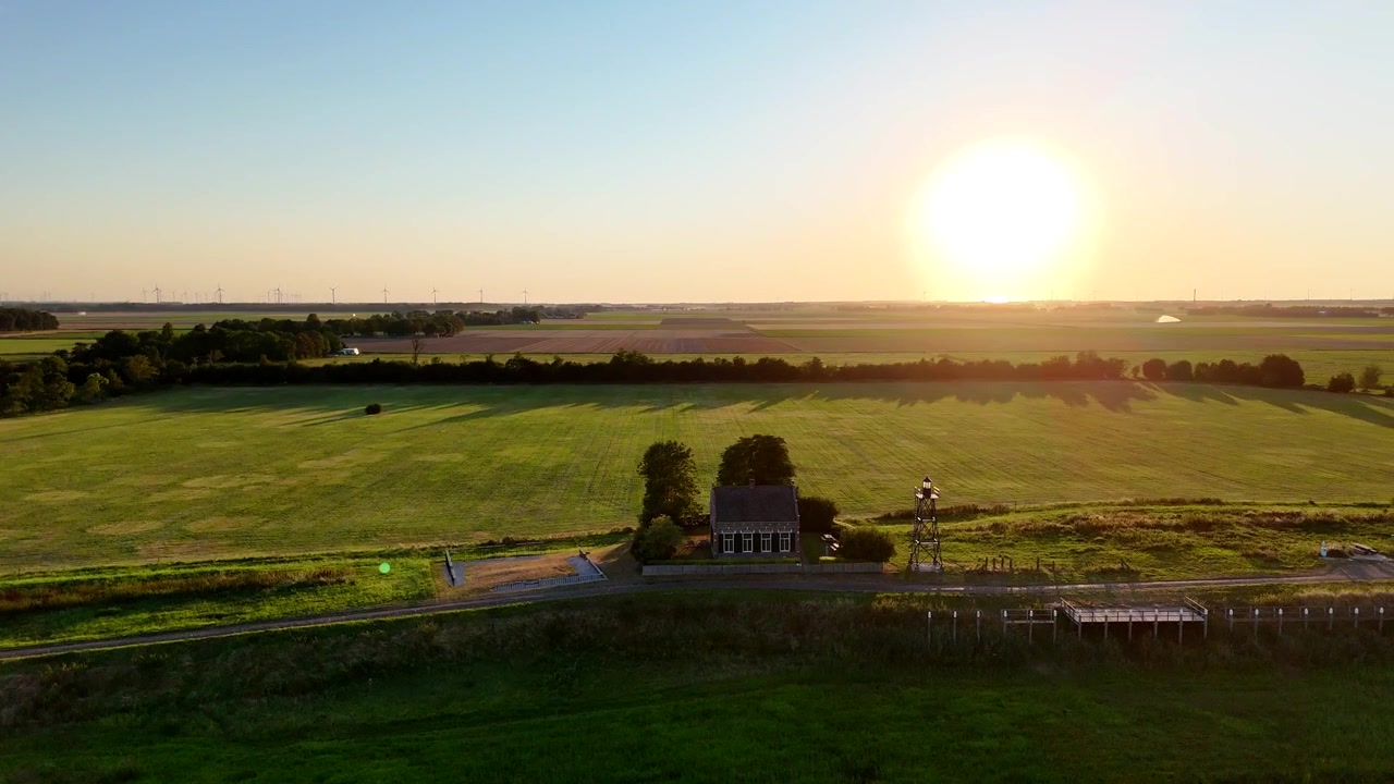 A scenic drone shot capturing the historic former island of Schokland in the Netherlands on a bright, sunny day. Rotating shot of Lighthouse en foghorn house with former harbor.