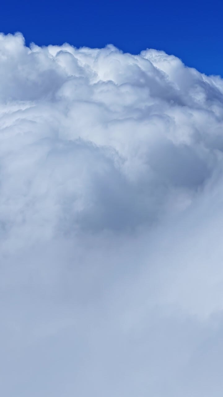 Fluffy White Cumulus Clouds Against A Clear Blue Sky. - aerial vertical shot