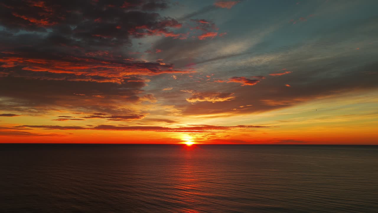Paesaggio marino aereo drammatico al tramonto con nuvole arancioni e riflessi della luce solare sull'acqua ad Alicante, Spagna, per concetti di viaggio e turismo