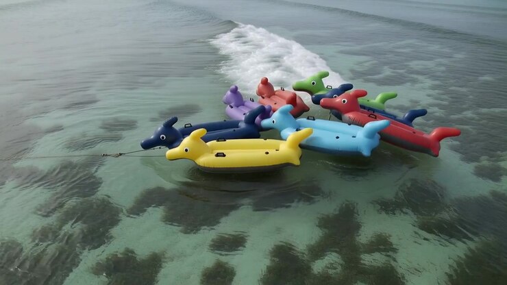 Bobbing inflatable dolphin cluster rotating, shifting on shallow water, swell arriving